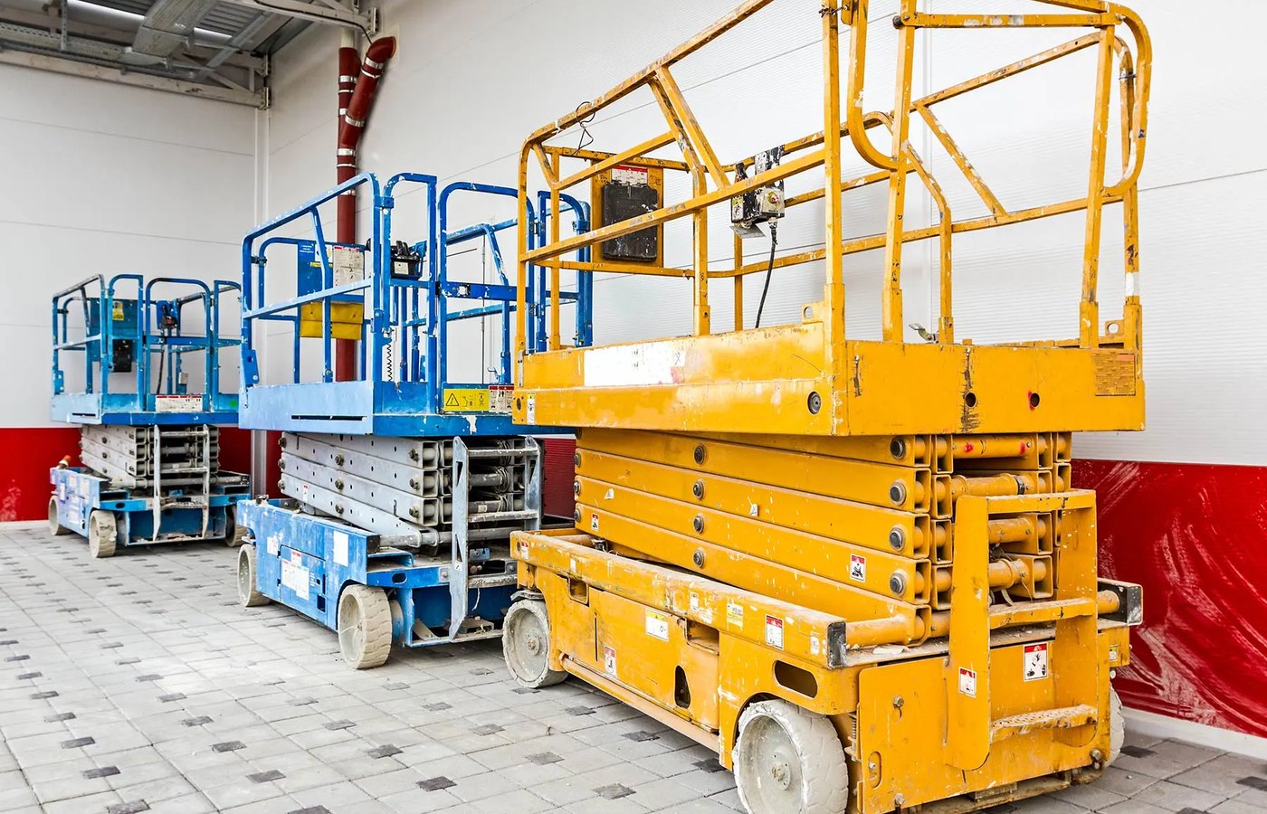 Scissor lift fleet staged inside an equipment facility